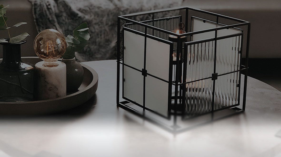 A Modern Impressions Votive Holder sitting on a marble coffee table.