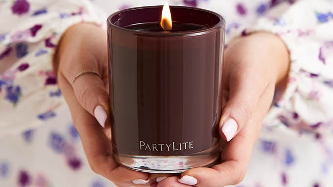 Woman holding a lit dark scented candle.